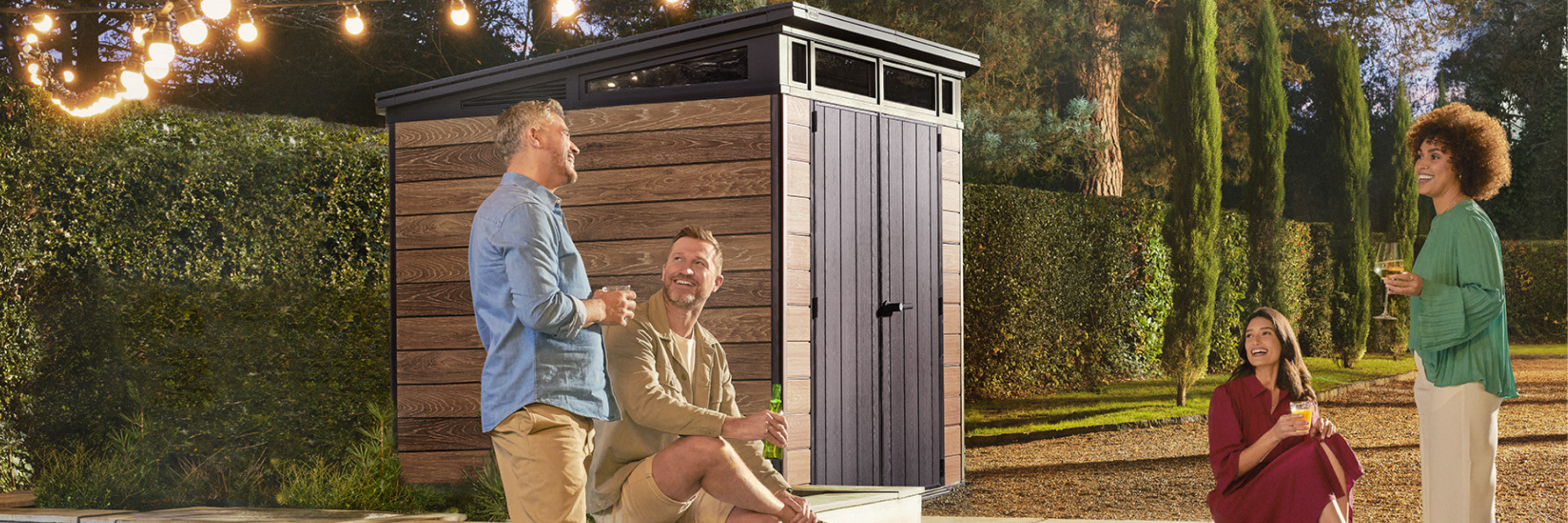 Friends enjoying an evening outdoors beside a Keter garden shed, showing how to organise outdoor areas stylishly and practically.