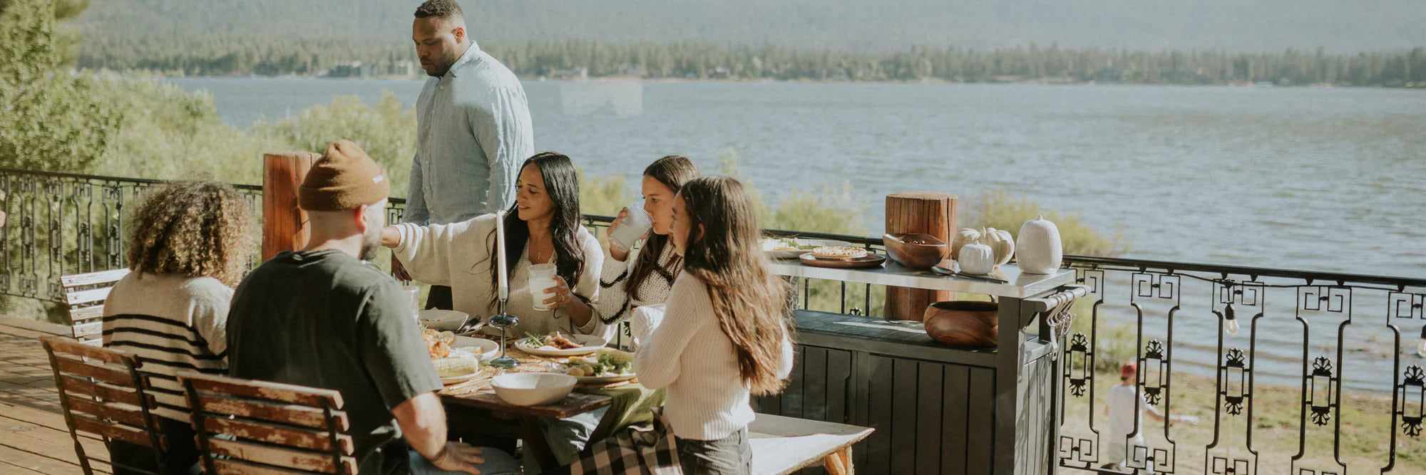 Family enjoying a meal outdoors beside a lake, surrounded by stylish recycled plastic garden furniture that reflects sustainable outdoor living in South Africa.