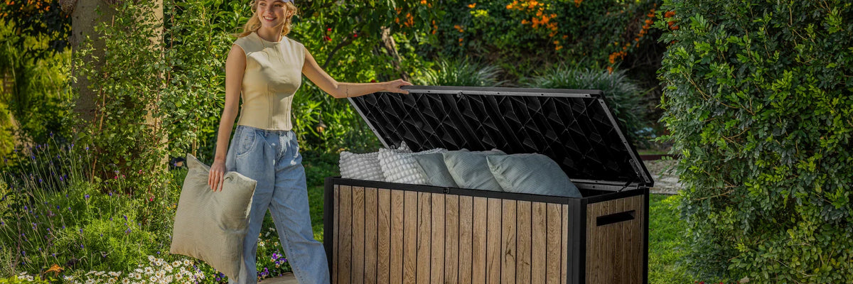 Woman using a Keter deck box for small yard storage solutions, showing a stylish and space-saving outdoor storage option in a compact garden.