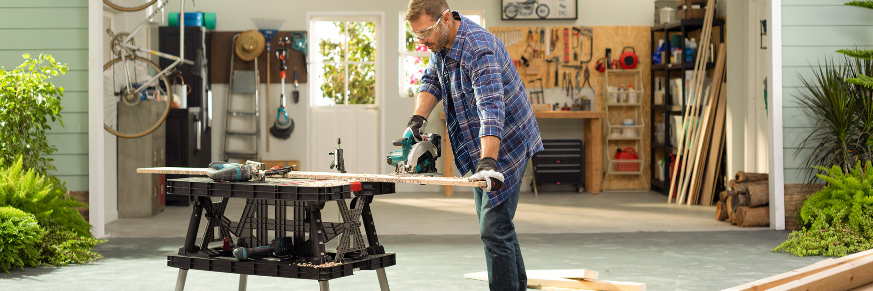 Man using mobile tool storage and work table in garage workshop