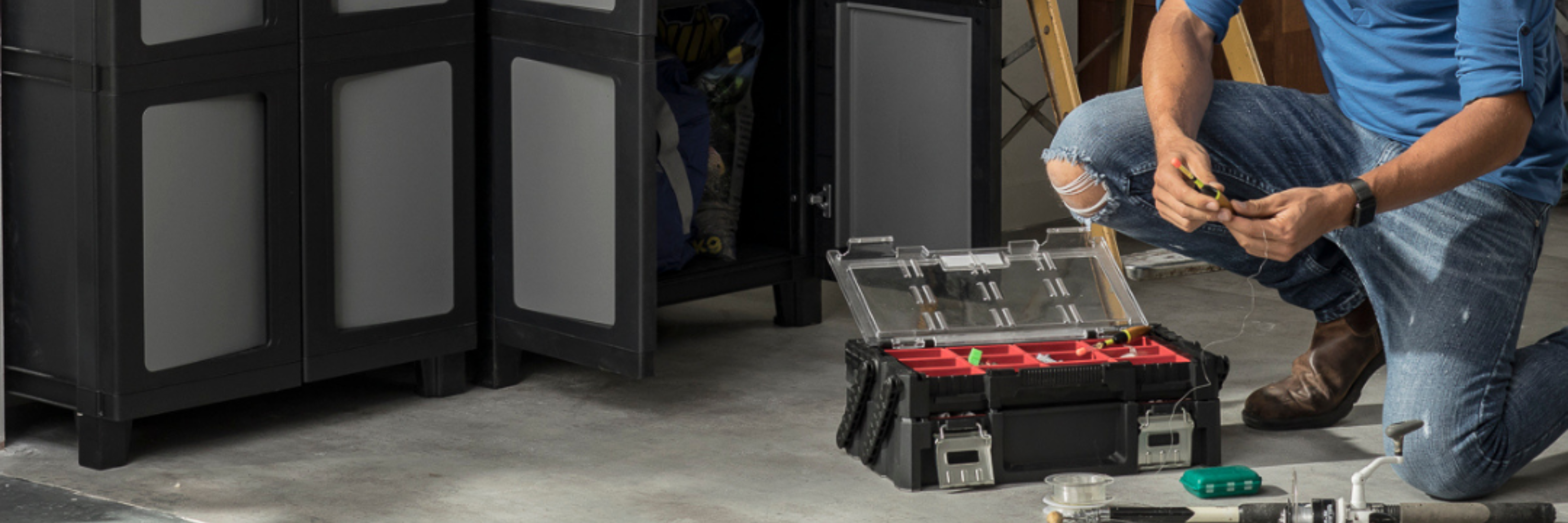 Keter storage organiser with compartments for screws and small parts in a garage workspace.