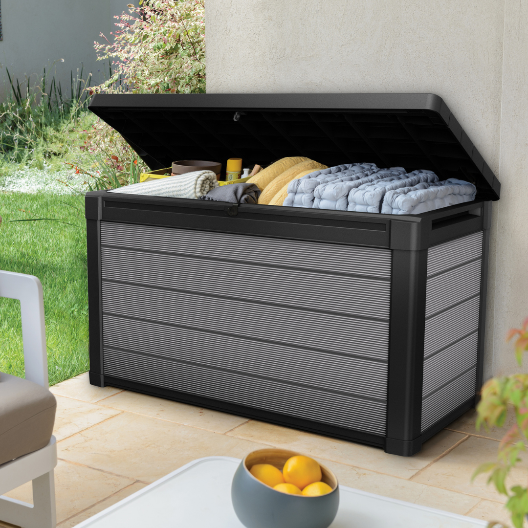 Premier 380L Storage Box with an open lid revealing folded blankets and cushions in a dark grey slatted-effect finish