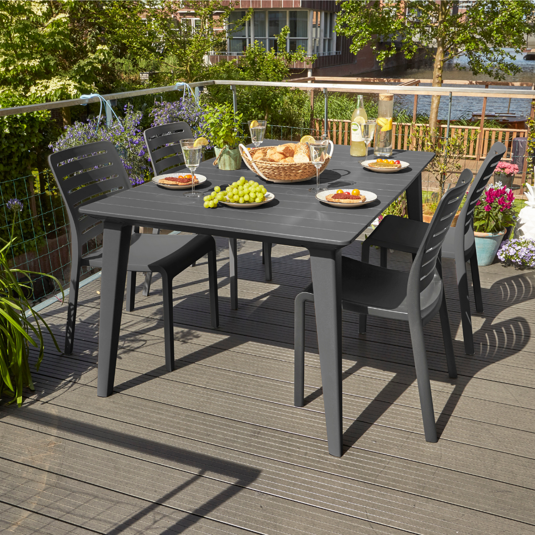 Lima Table Graphite with a rectangular wood look resin top surrounded by dining chairs on a sunny deck