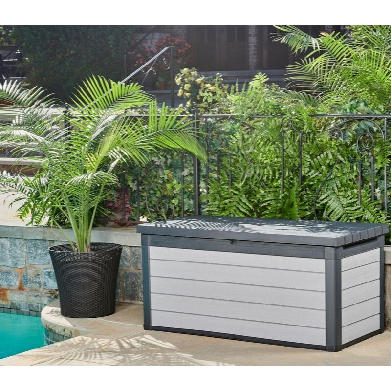 Denali 570L Storage Box in grey with a dark slatted lid and woodgrain effect panels beside a pool in a leafy garden