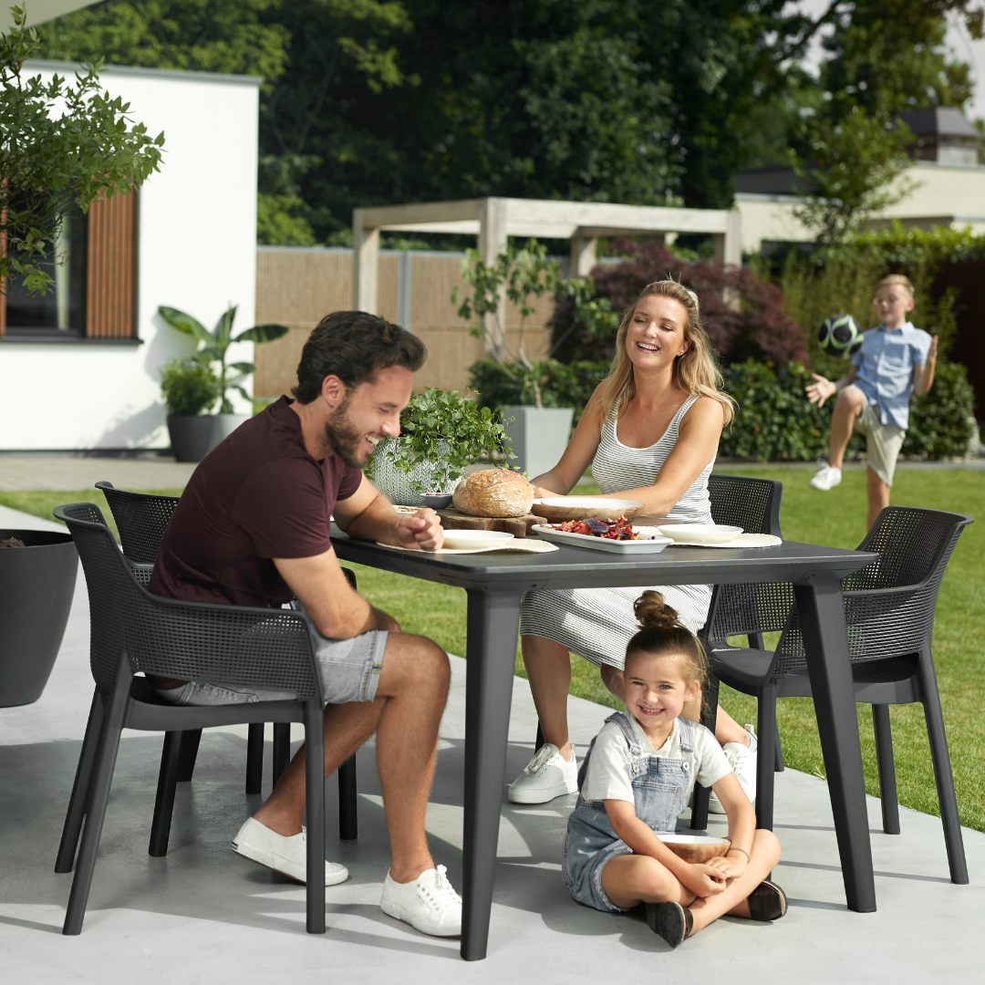 Lima Table Graphite with a wood-look textured surface surrounded by chairs during a family meal in the garden