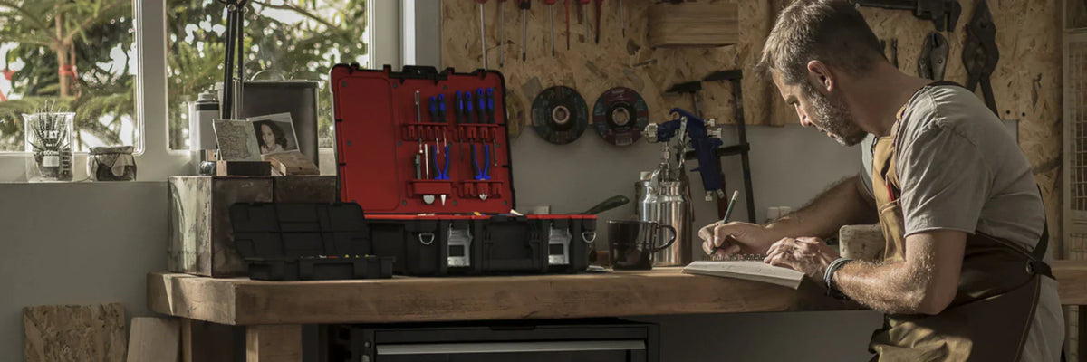 Man working at a workshop bench with organised toolboxes and garage storage solutions for efficient workspace organisation.